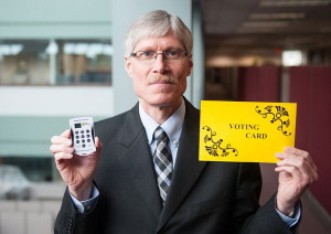 Мирон Айсенжер держит устройство дистанционного голосования, которое будет использоваться вместо прежних желтых карточек
