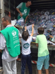 Сотрудники АДРА и школьники, загружающие комплекты личной гигиены на грузовик в Бразилии. (АДРА ANN)