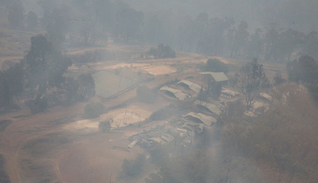 Лагерь Логу Брук виден с воздуха все еще сквозь густой дым. (Марк Пизи / Adventist Record)