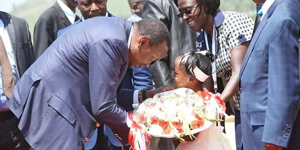 Президент Кении Ухуру Кеньятта, говорит с девочкой на церемонии посвящения в Кисуму. (ECD)