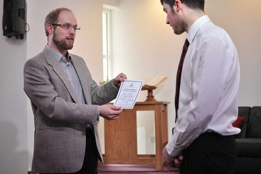 Хьюз получает свое свидетельство о крещении от пастора Чарльза Летбриджа. (С разрешения Джимми Бота / БУК)