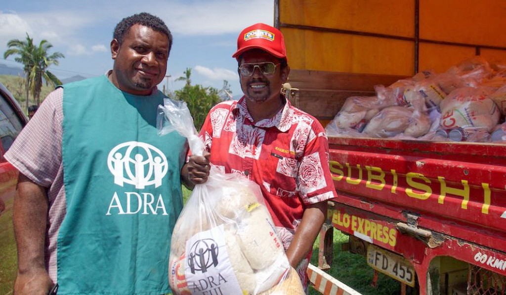 Сотрудники АДРА, распределяющие еду в Фиджи. (АДРА)