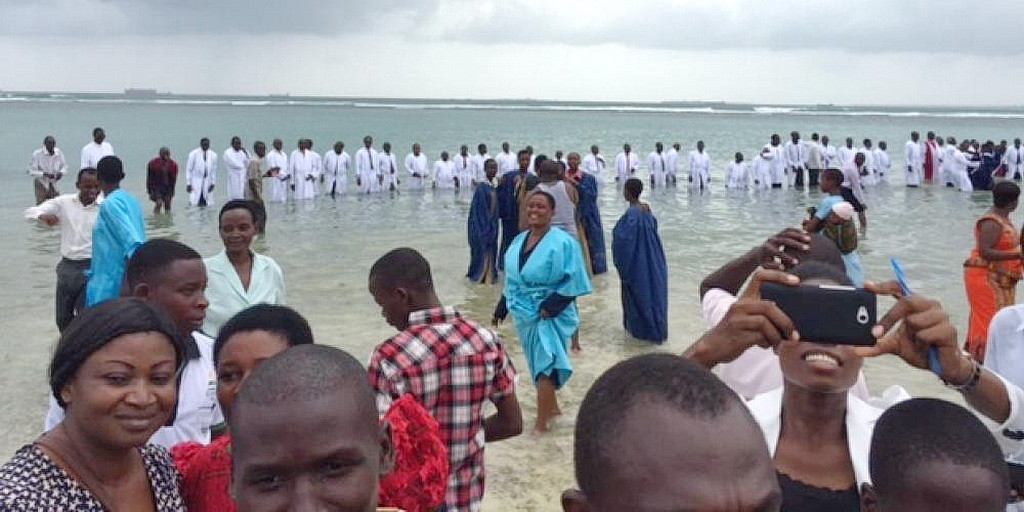Пасторы, собравшиеся в воде после крещения 2 309 человек в Танзании в 2015 году. Крещения в Руанде, как ожидают, достигнут 100 000 человек.
