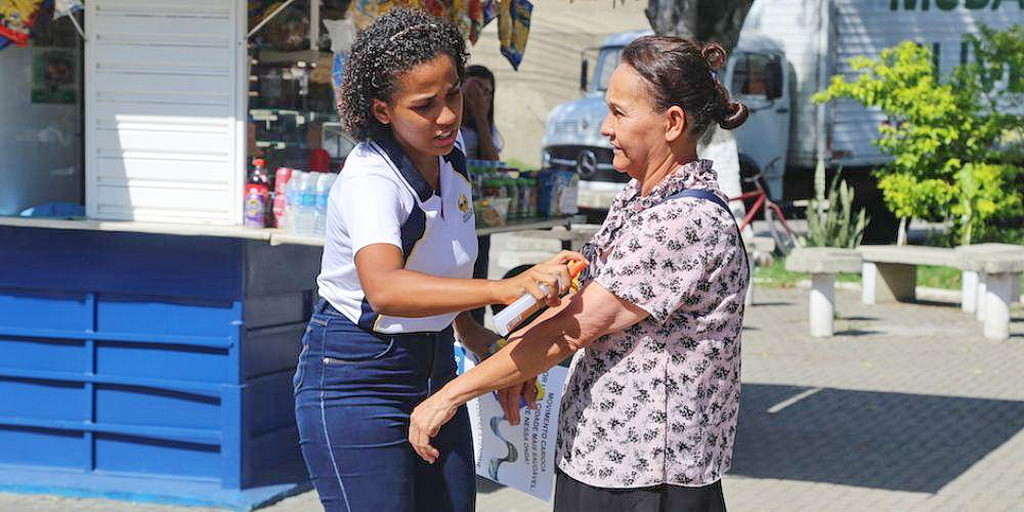 Молодая женщина, распыляющая средство против насекомых на прохожего, во время кампании против вируса Зика в Бразилии. (Фотографии: SAD)