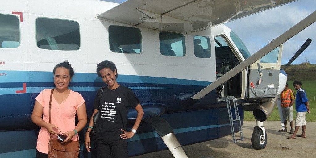 Два работника АДРА стоят около частного самолета Мела Гибсона на острове Мэго, Фиджи. (Adventist Record)