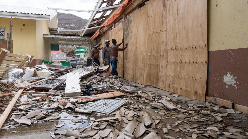 Мужчины в Род-Тауне забивают витрину, готовясь к урагану Мария в области, уже опустошенный Ирмой. [Фото: ADRA International]
