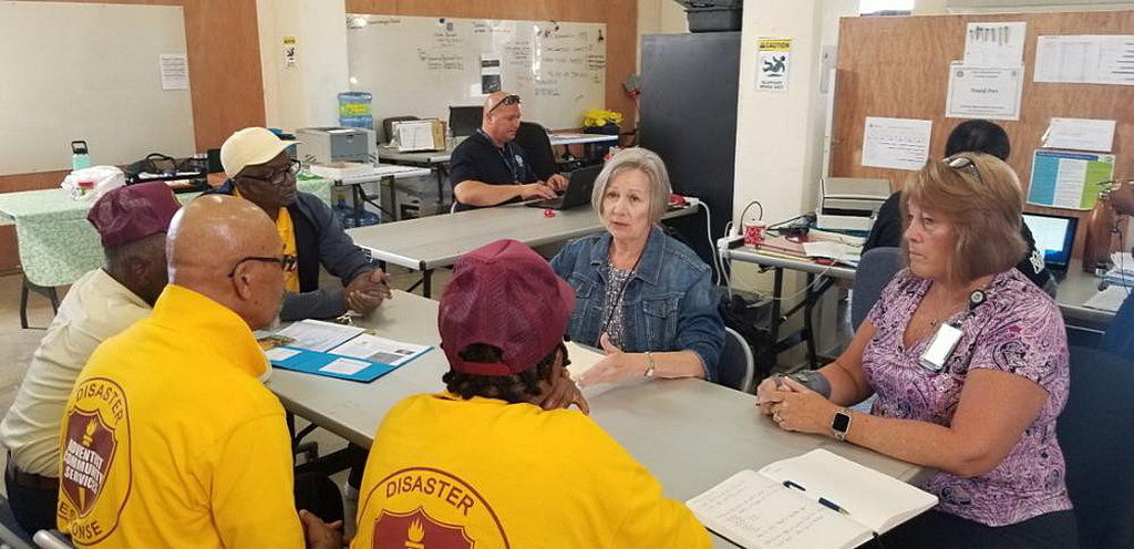 Представители Федерального агентства США по чрезвычайным ситуациям (FEMA) беседуют с волонтерами Адвентистского Общественного служения (ACS). [Фото: В. Деррик Ли, Адвентистское Общественное Служение]