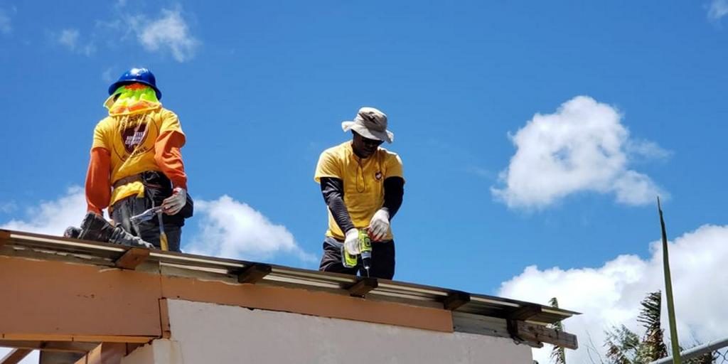 Добровольцы Адвентистского Общественного служения работают над заменой крыши, поврежденной Супер-тайфуном Юту на Северных Марианских островах. [Фото: В. Деррик Ли]