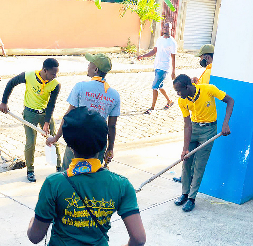 Несколько молодых адвентистов из местного адвентистского молодежного общества вместе работают над уборкой перед полицейским участком в городе Милот, на севере Гаити, 12 июня 2022 года. [Фото: Миссия Северного Гаити]
