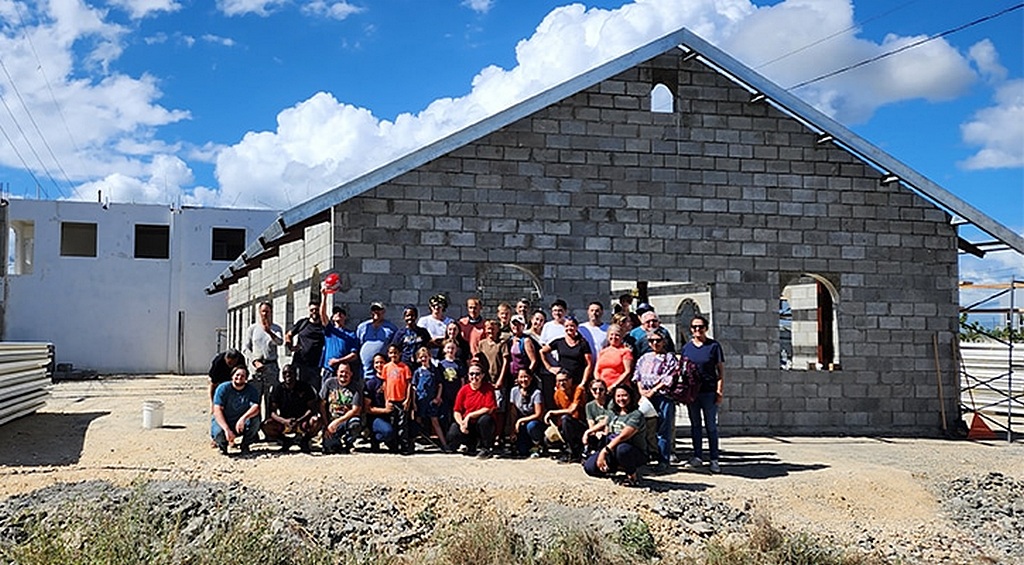 Волонтеры "Маранафа" позируют для группового фото на фоне новой церкви, которую они помогли построить в Санто-Доминго, Доминиканская Республика, в декабре 2022 года. (Фото: Maranatha Volunteers International)